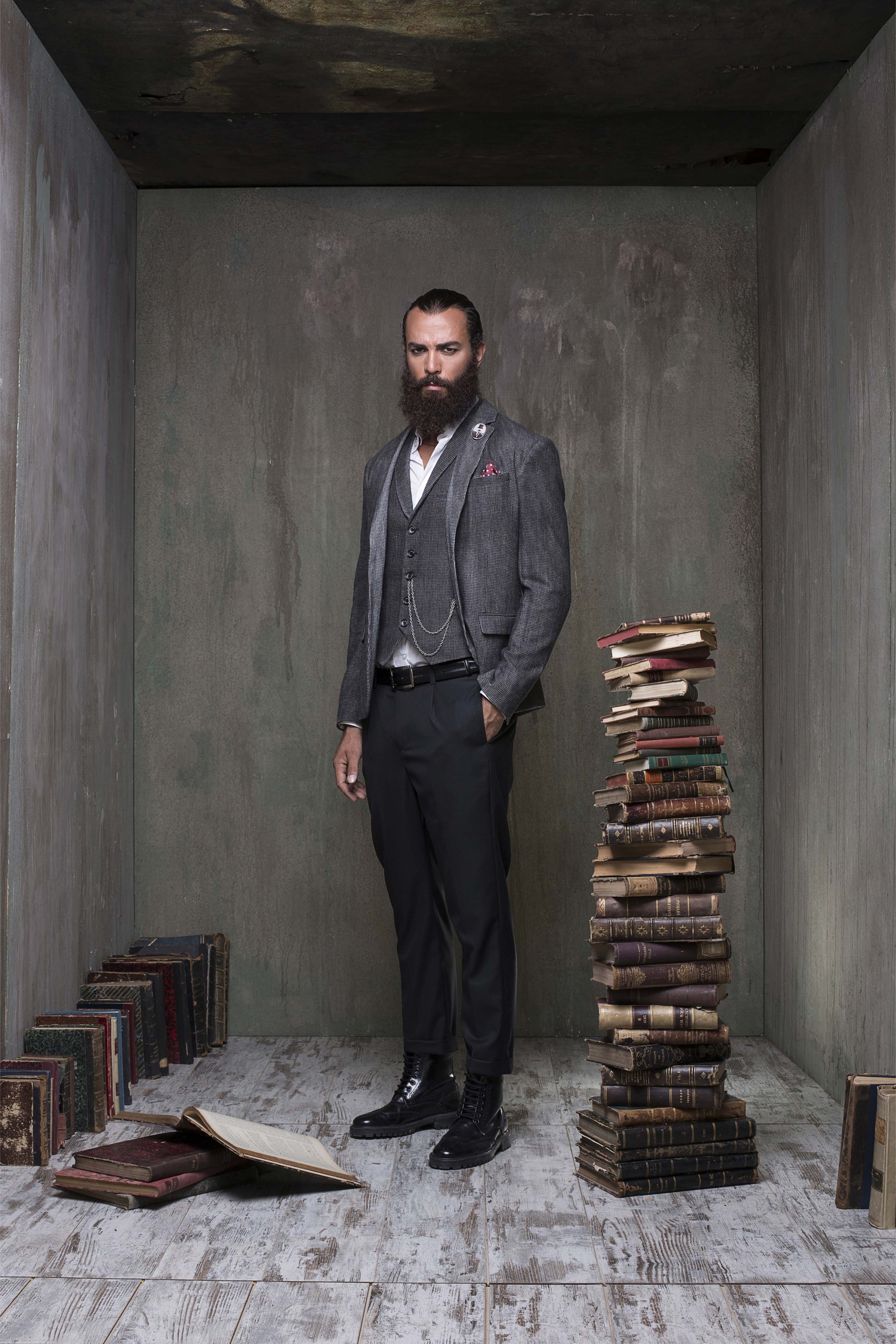 Three-piece tweed suit with a waistcoat and watch chain, beside a tall stack of antique books
