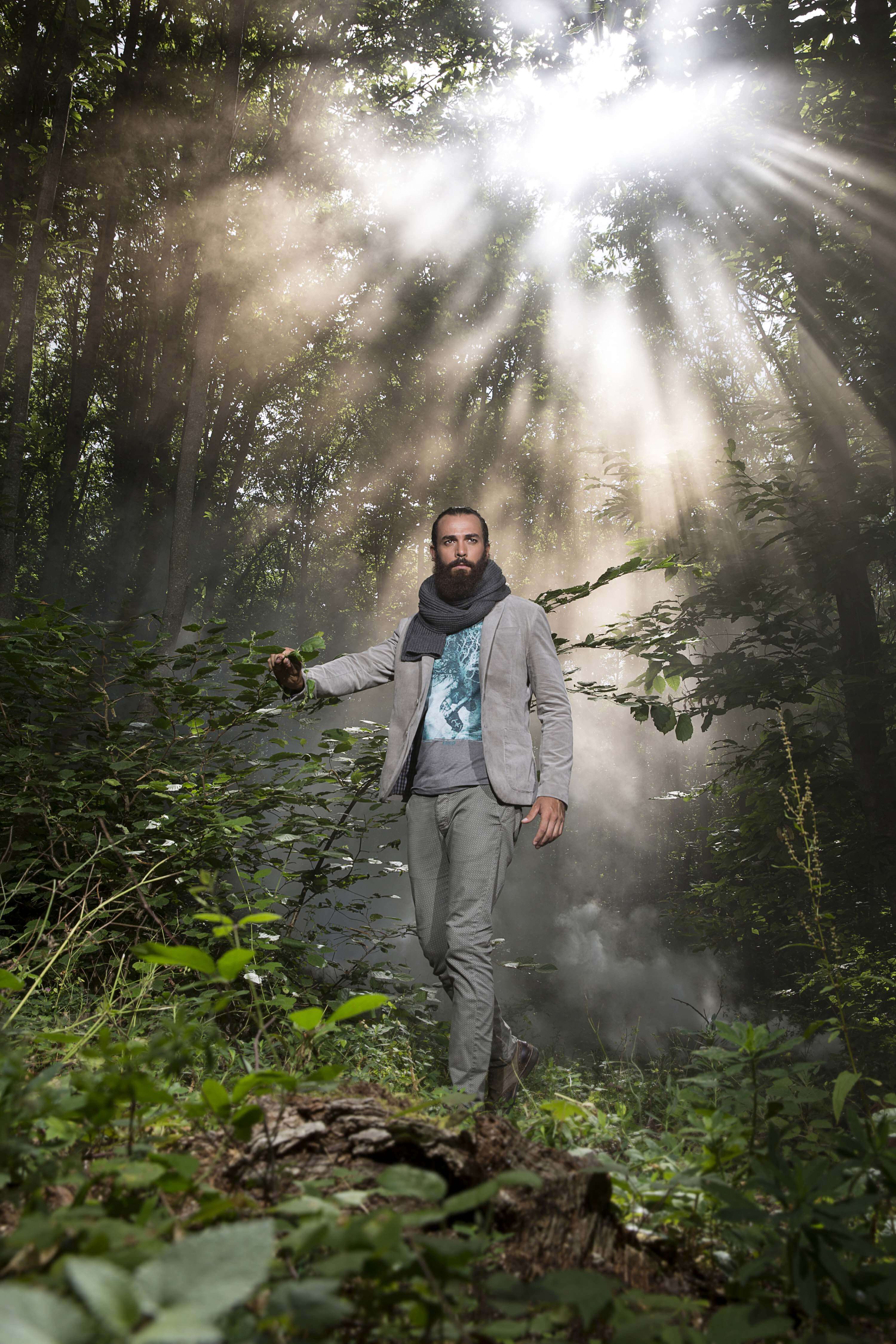 Grey jacket and scarf, the model walking through a sunlit misty forest