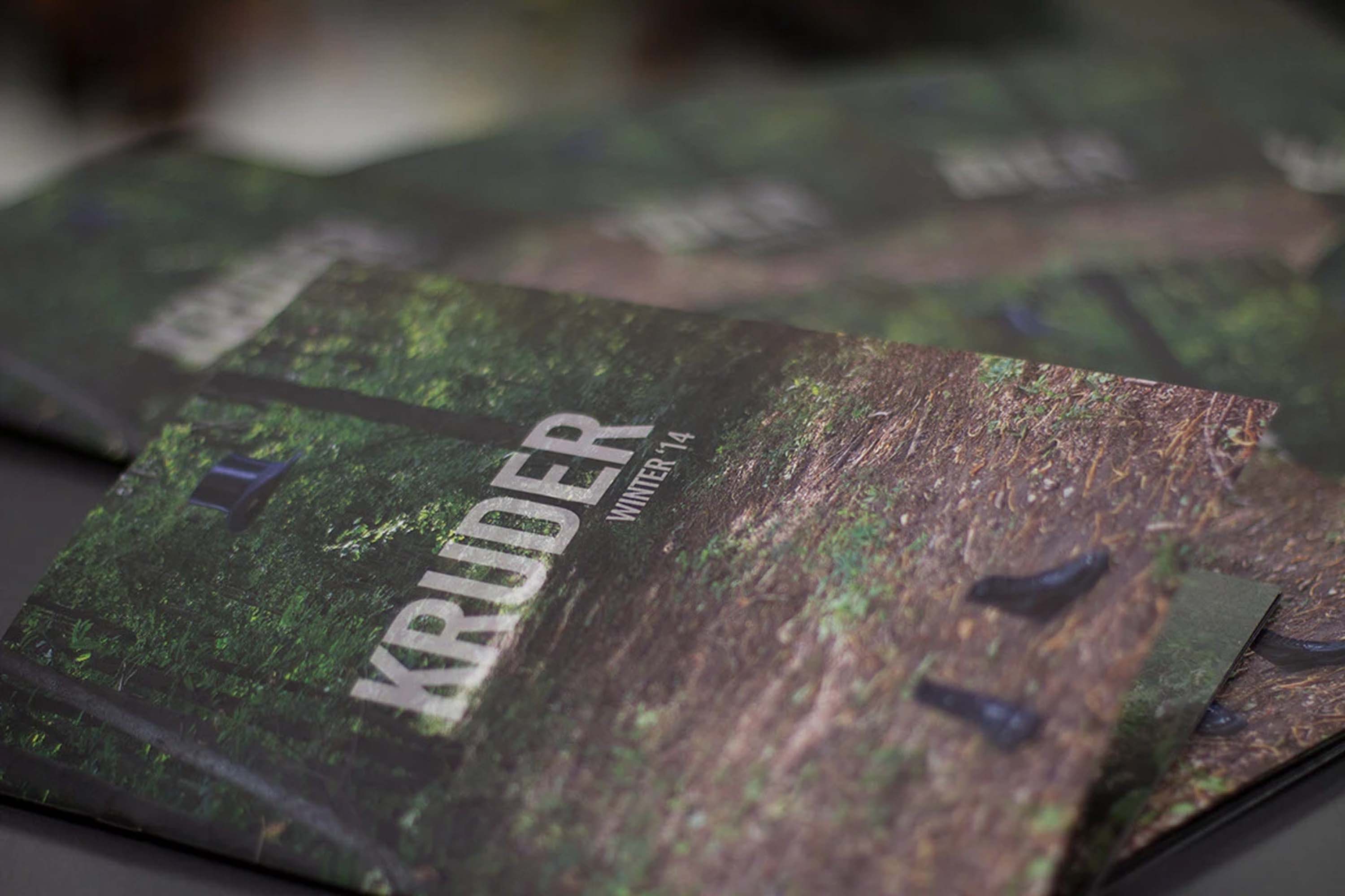 The printed Kruder Winter '14 lookbook, forest cover, stacked copies on a table