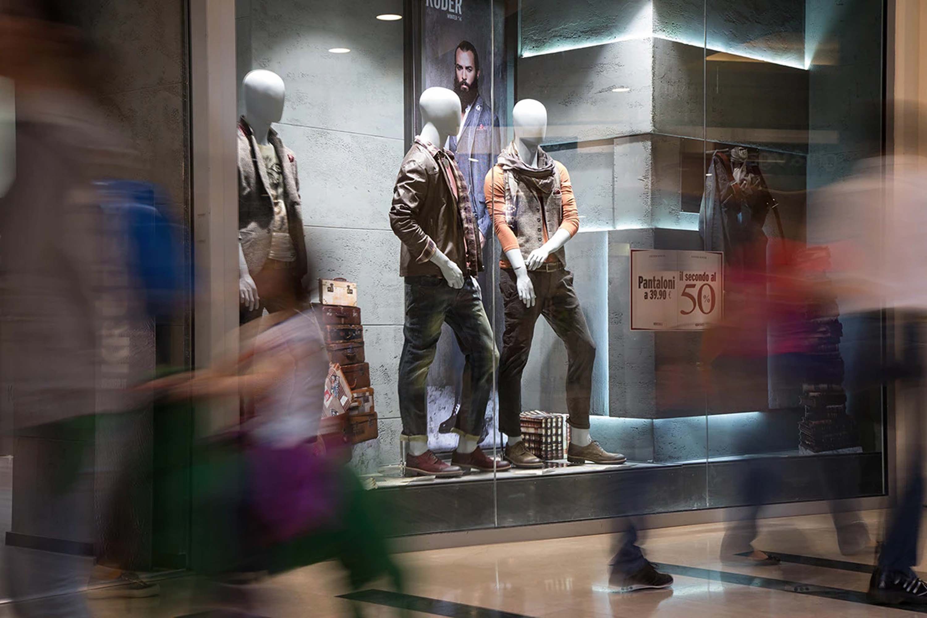 The Kruder shop window with mannequins and vintage suitcases, blurred passers-by and a fifty-per-cent sale sign