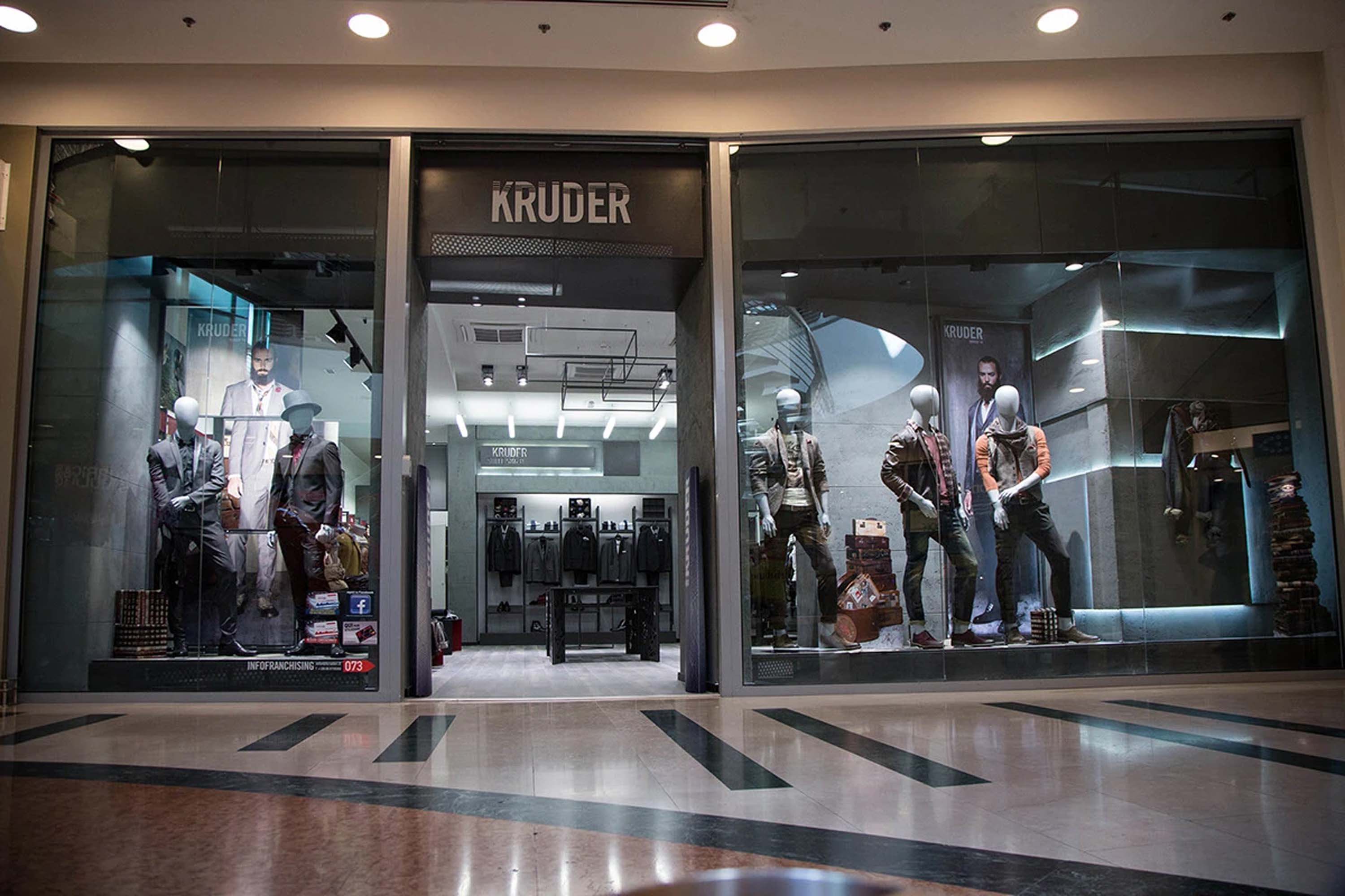 The Kruder storefront in a shopping mall, lit windows with mannequins and the Kruder sign