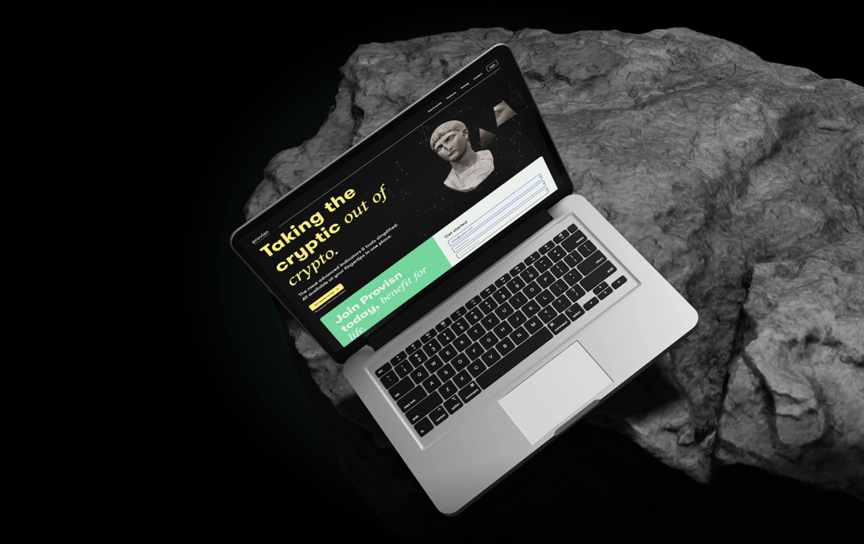 Closing shot — the landing page on a silver laptop seen from above, open on a rock against a black backdrop