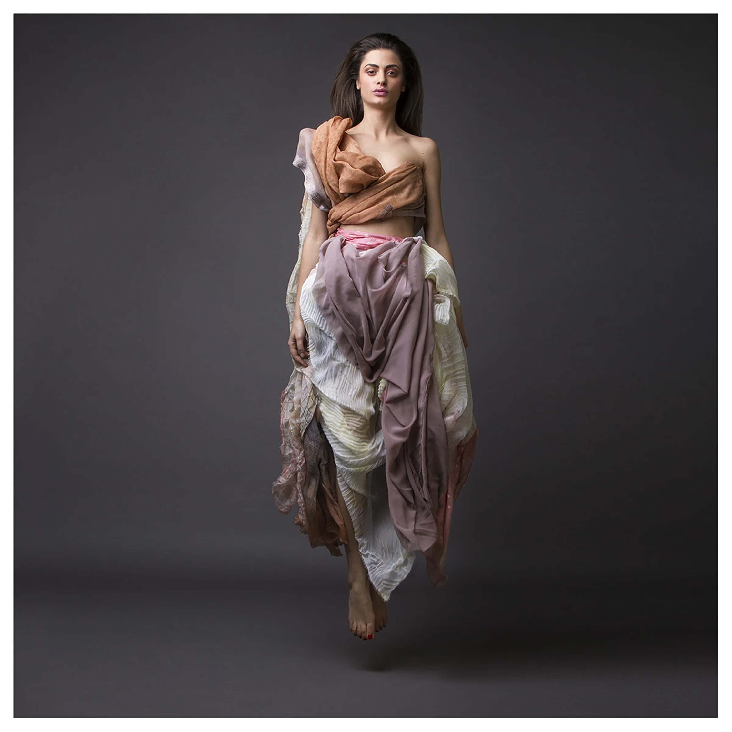The same look photographed in mid-air, barefoot and suspended, the layered skirt spread open by the jump