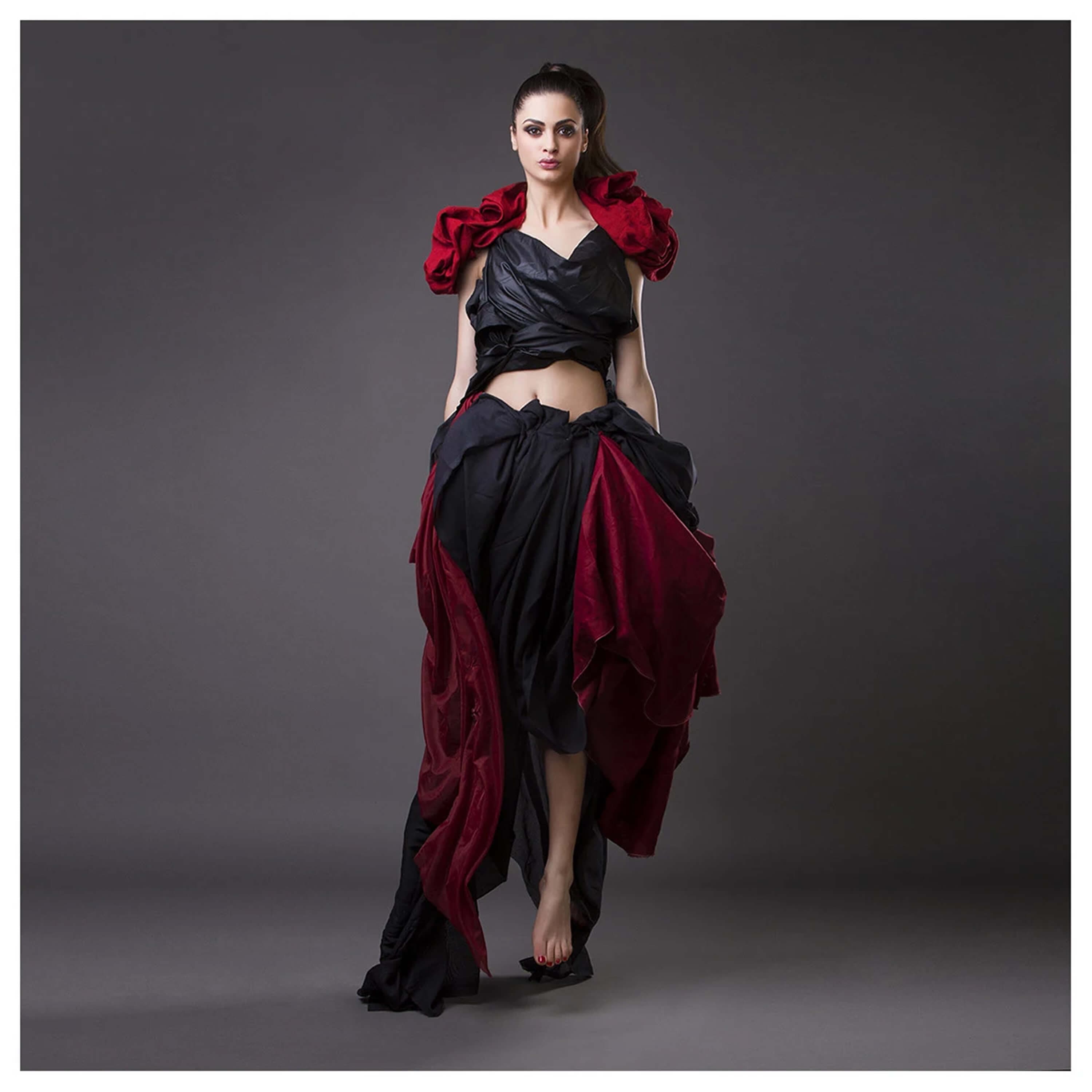 The black and red look full length, facing the camera, the ruffled red shoulders framing the draped silk skirt