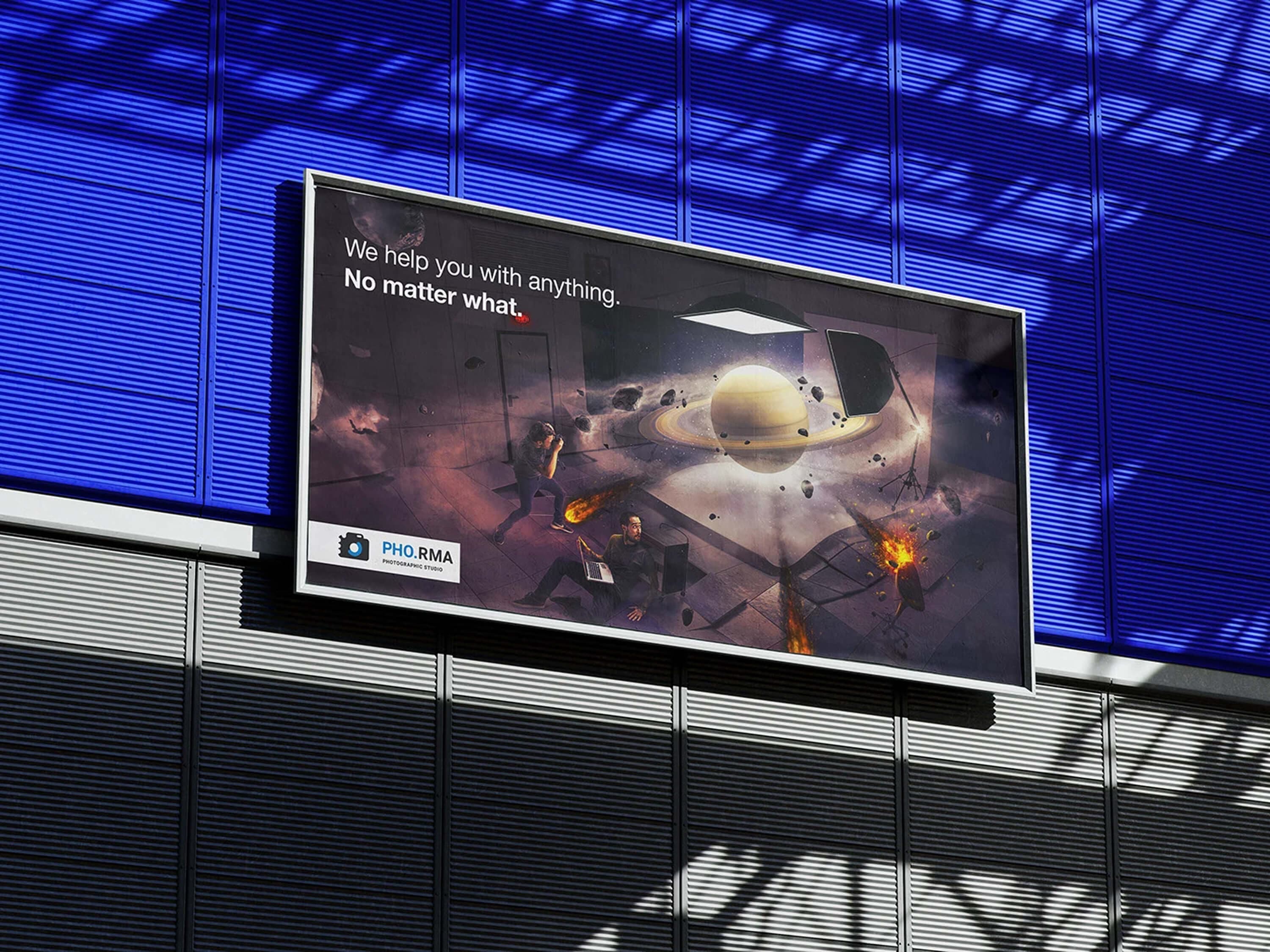 The Saturn billboard seen from below on the blue louvred facade, with the campaign line and the PHO.RMA photographic studio logo in the corner